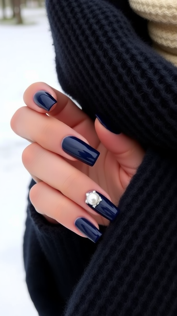 Close-up of hands with navy blue nails featuring pearl detailing.