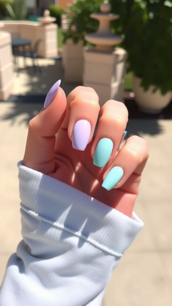 A hand displaying pastel lavender and mint green nail polish against a sunny background.