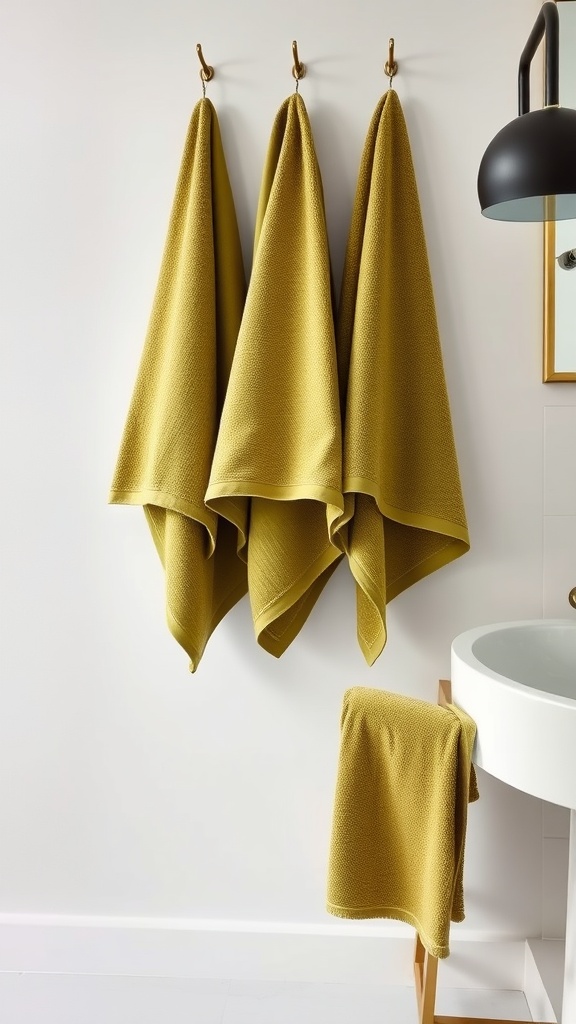 Olive green towels hanging on hooks in a bathroom setting.