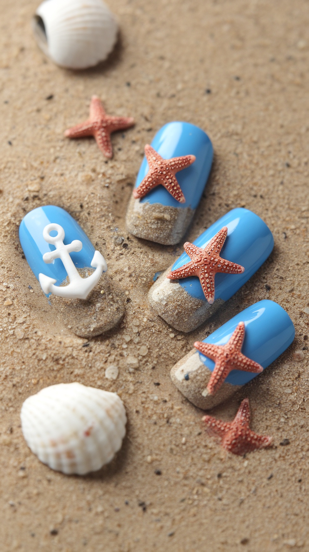 Nail design featuring beachy sand textures, blue polish, starfish, and an anchor.