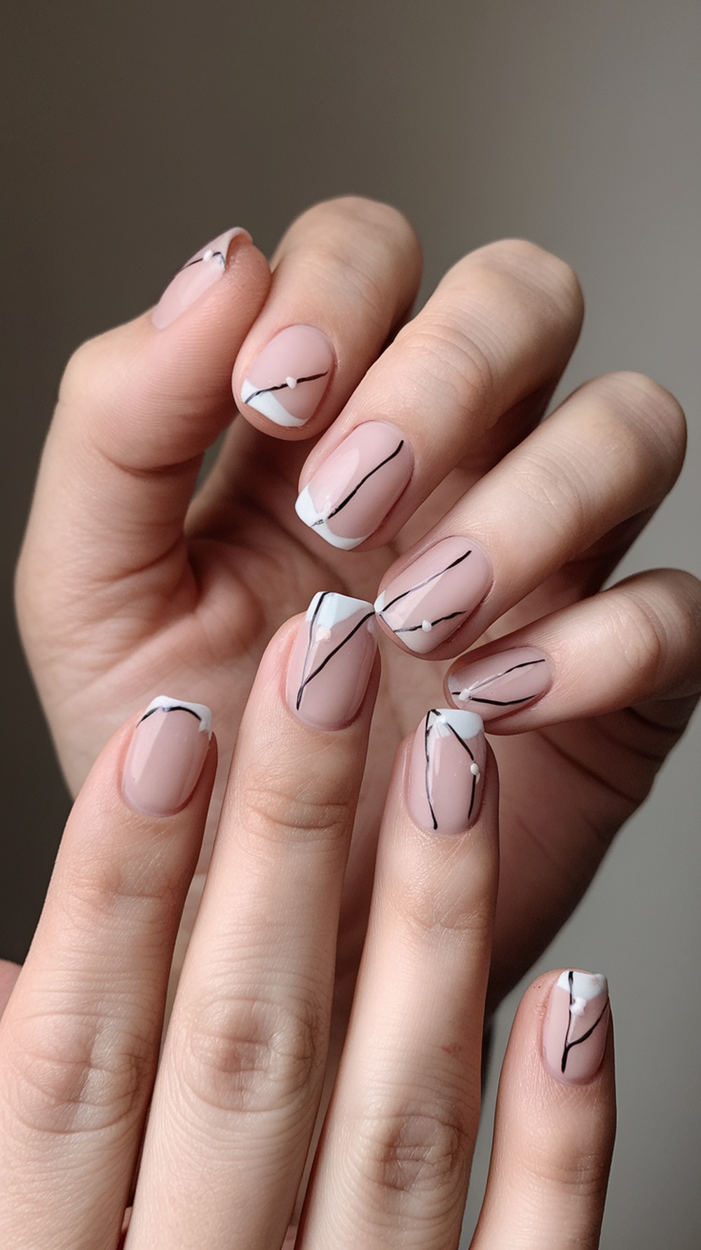A close-up of minimalist summer nails featuring a nude base with black and white designs.