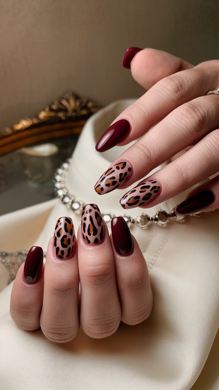 Nails painted in dark cherry red with leopard print design