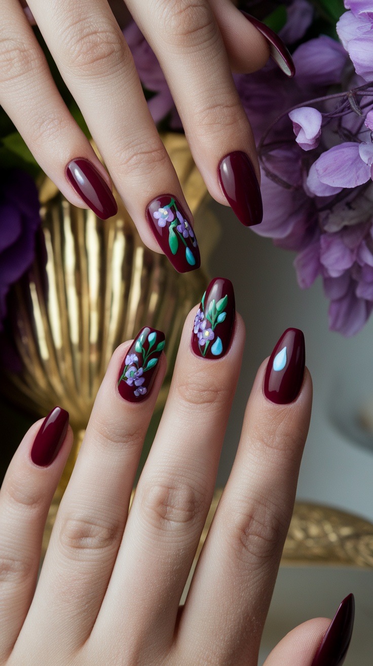 Close-up of hands with cherry red nails featuring floral designs in jewel tones.