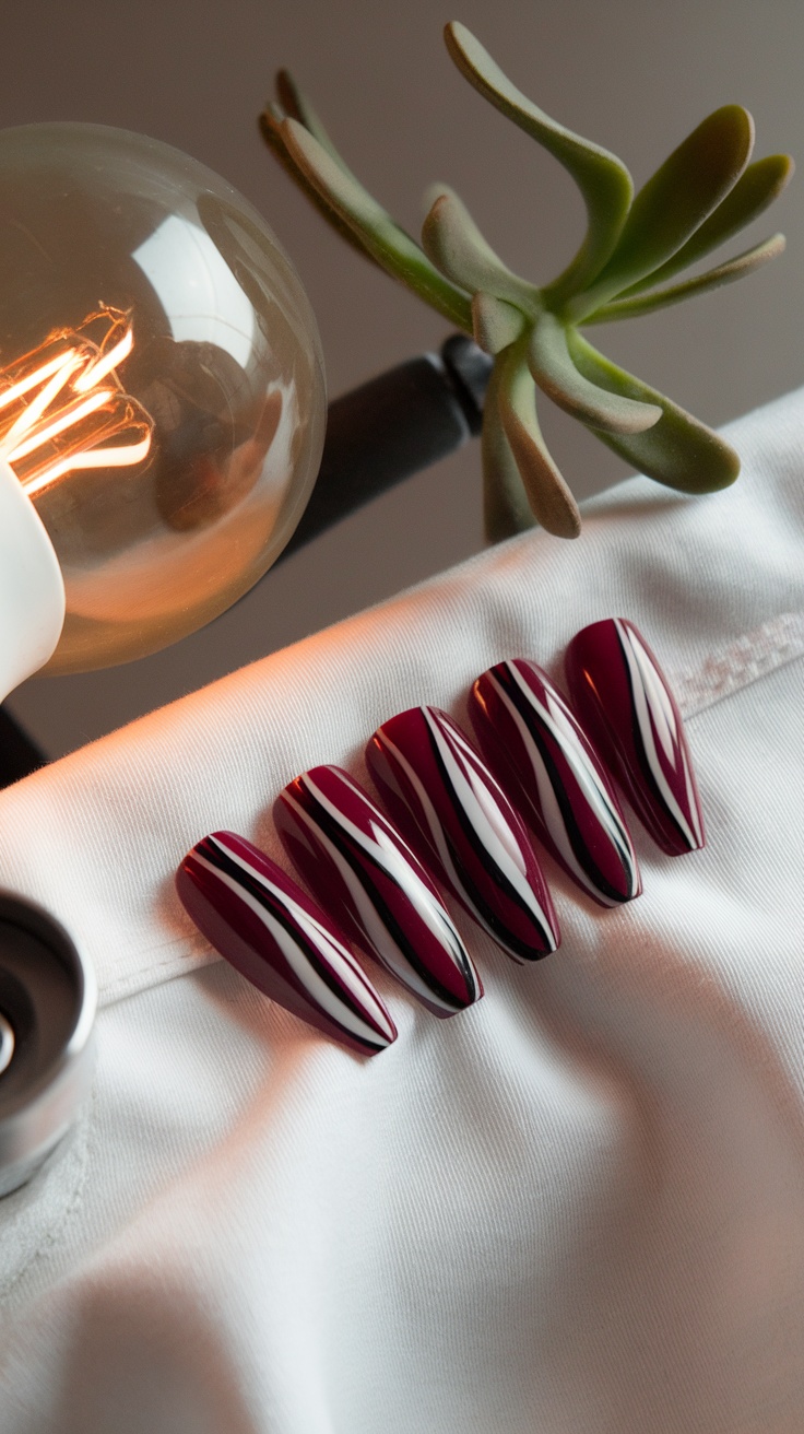 A set of cherry red nails with striking black and white lines on a white fabric background.