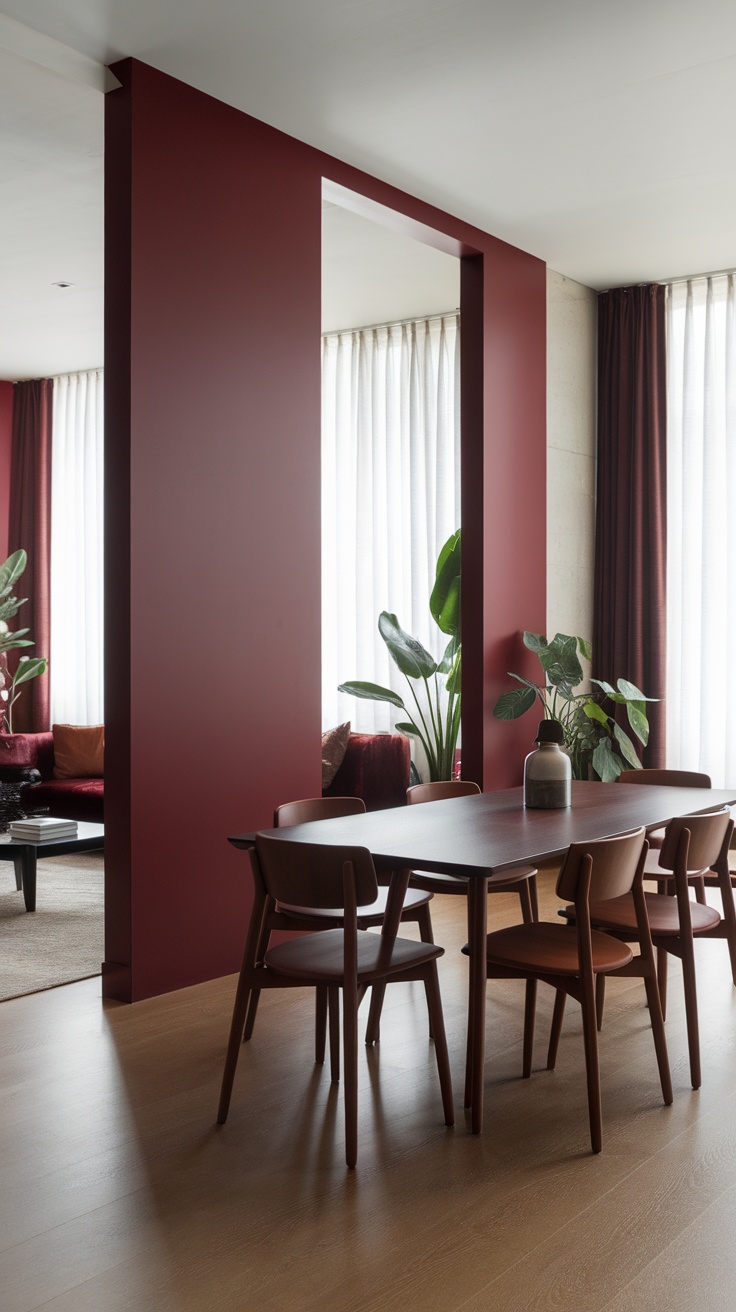 A contemporary dining room featuring dark cherry red walls, a wooden dining table, and elegant chairs, with plants and large windows letting in natural light.