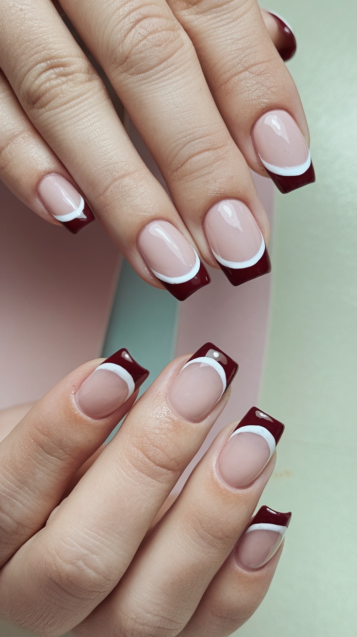 Close-up of manicured nails featuring a French tip design with cherry red tips and a nude base.