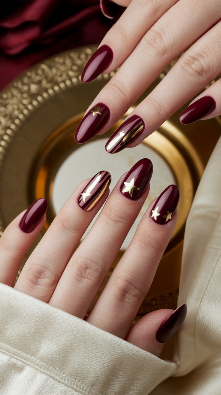 Close-up of dark cherry red nails with gold star and stripe designs on a gold background.