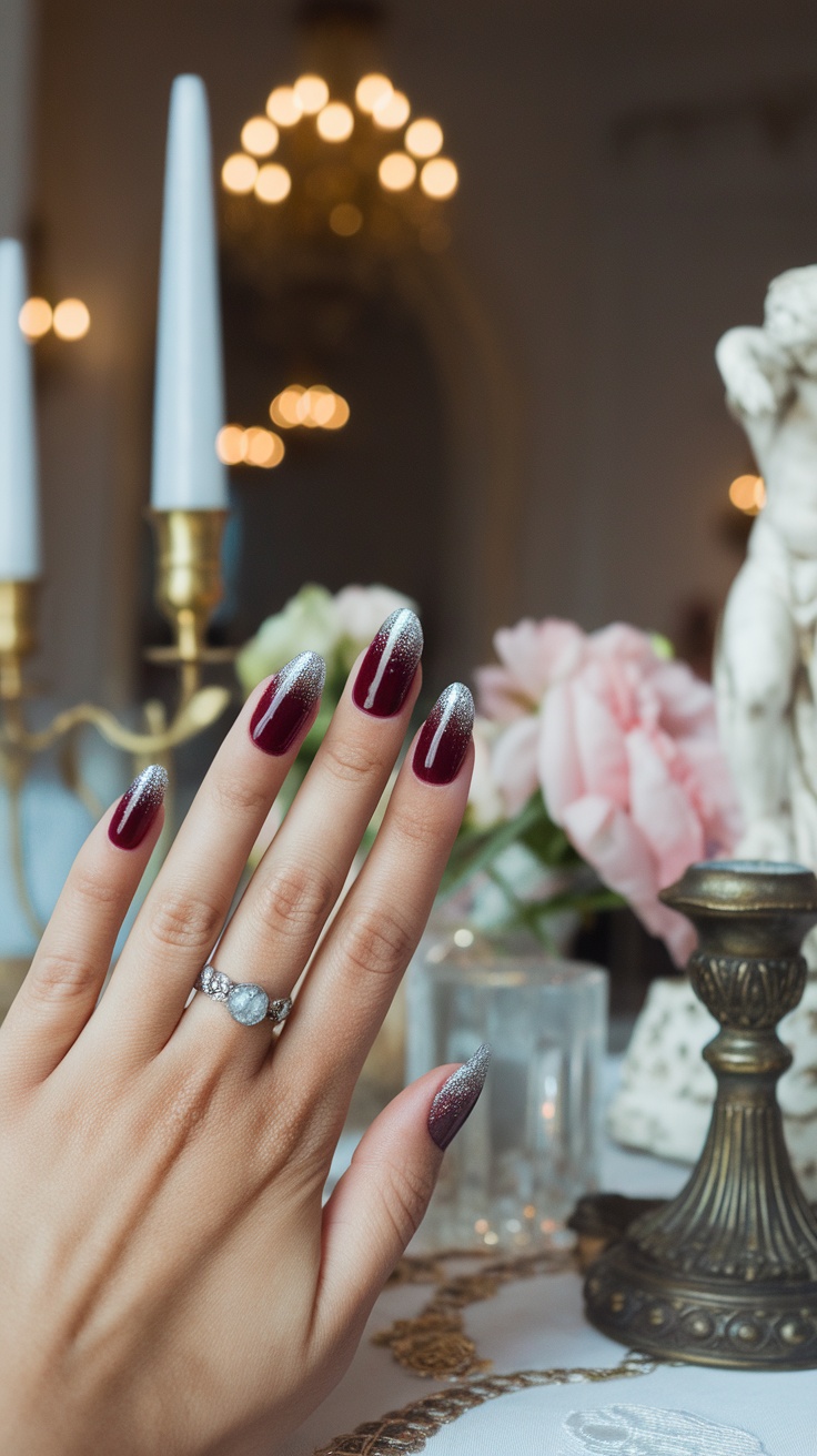 Close-up of a hand with dark cherry red nails featuring a glitter ombre effect, set against a stylish backdrop