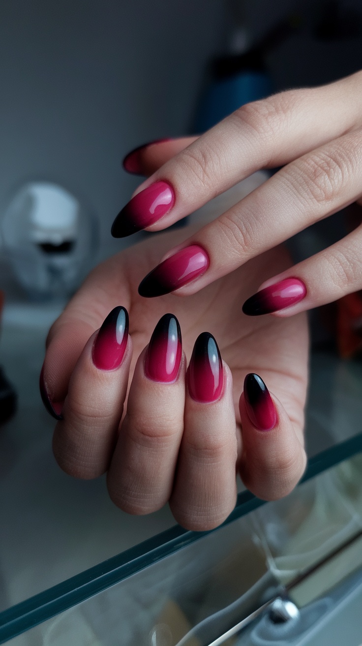 A hand showing gradient fade nails from dark cherry red to black tips.