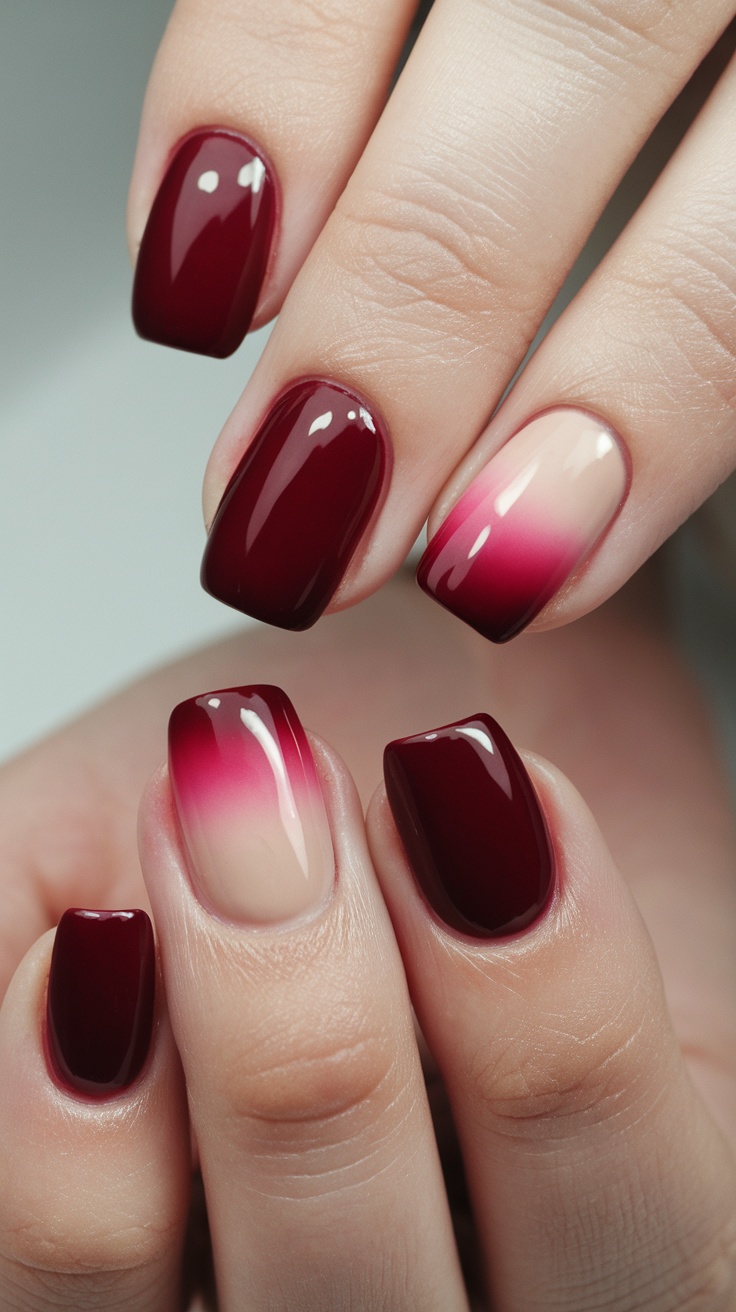 Close-up of nails featuring a soft ombre design that transitions from dark cherry red to a lighter shade.