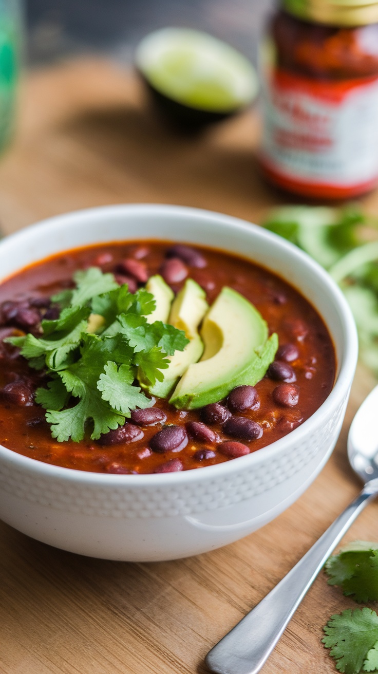 A bowl of spicy black bean soup garnished with cilantro and avocado slices.