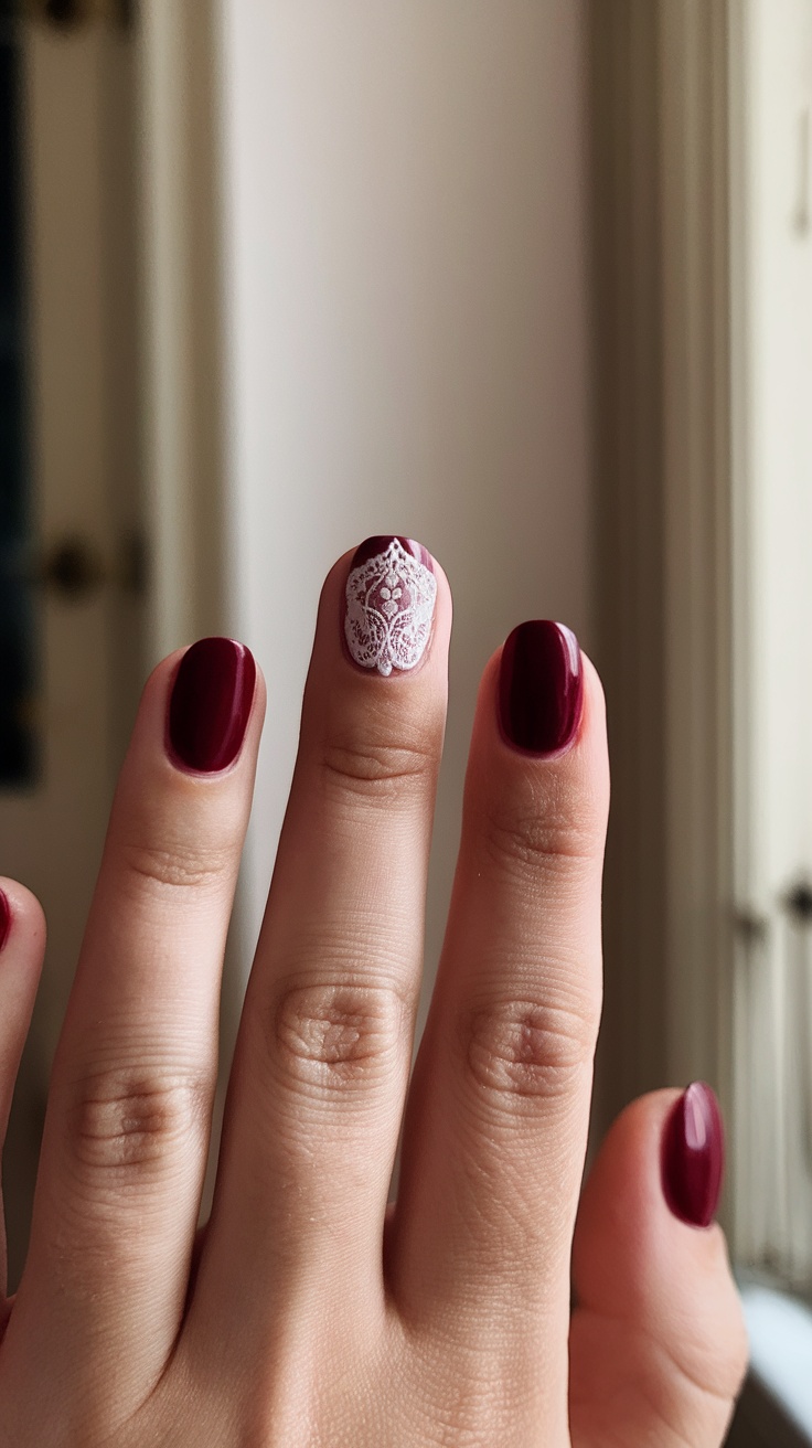 Dark cherry red nails with a vintage lace design on one finger.