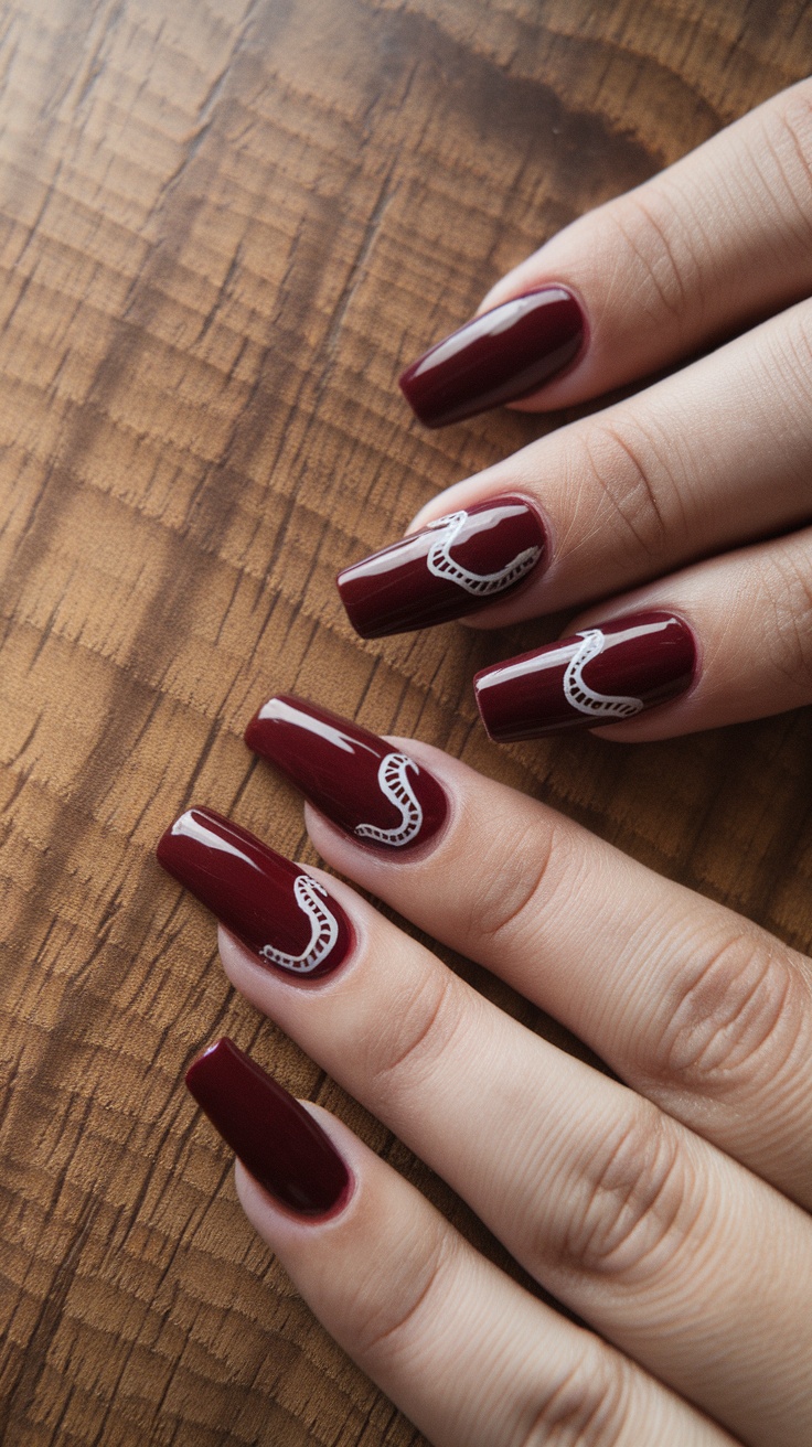 Nails painted in dark cherry red with white wave designs on a wooden surface.