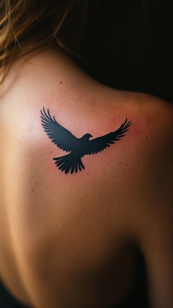 Minimalist silhouette tattoo of a bird in flight on a person's back.