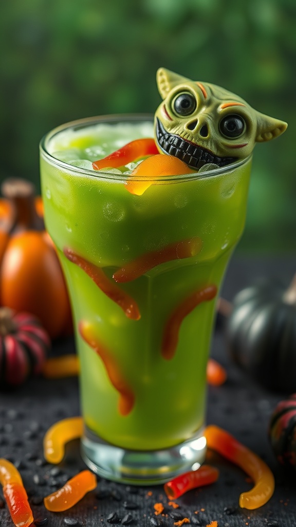 A green mocktail with gummy worms and a spooky goblin figure on top, surrounded by Halloween decorations.