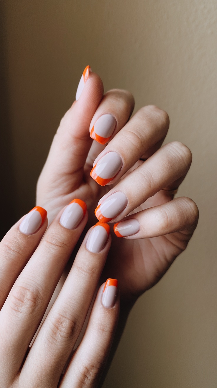 Close-up of hands with nails featuring bold orange tips on a soft base.