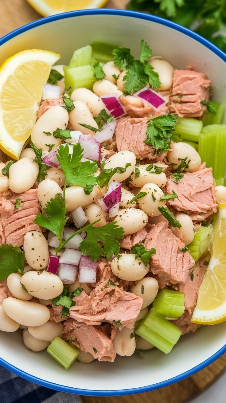 A bowl of tuna and white bean salad with celery, red onion, and lemon wedges