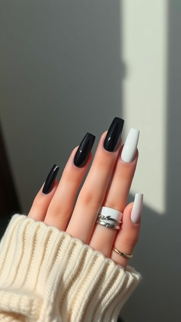 Close-up of hands with black and white acrylic coffin nails, wearing rings and a cream sweater.