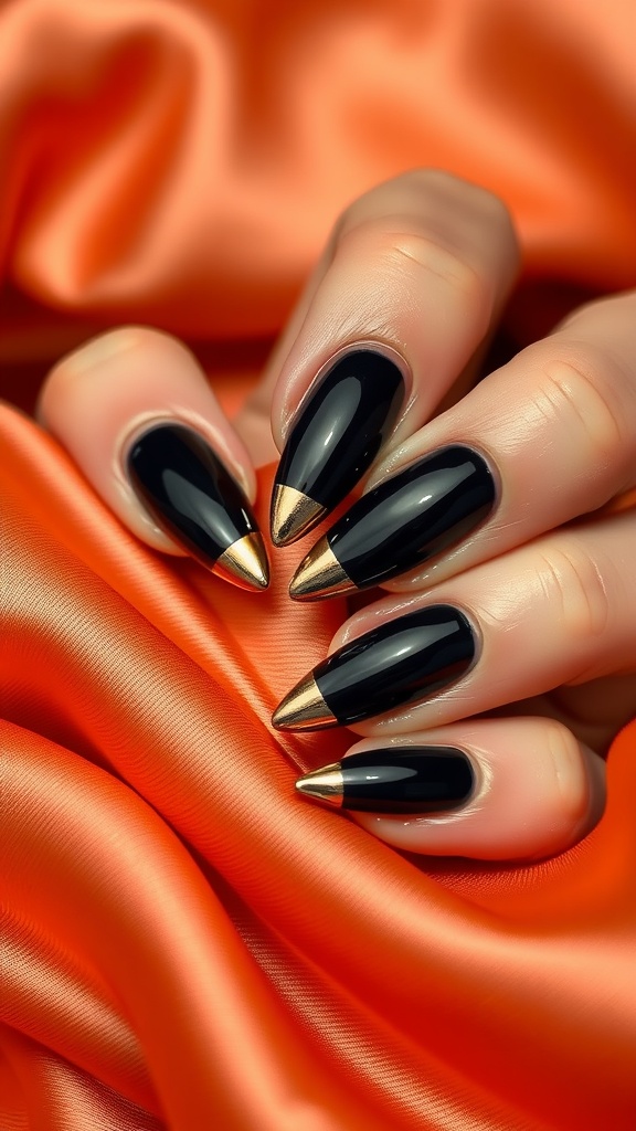 Dramatic black nails with gold foil tips on an orange satin background.
