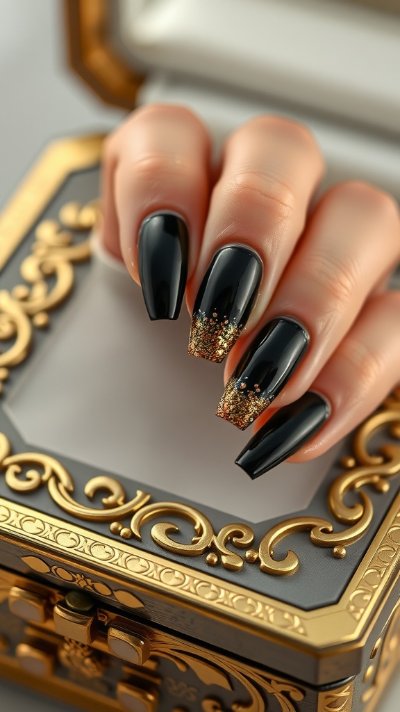 A hand displaying gradient black nails with gold glitter tips, resting on an ornate black and gold jewelry box.