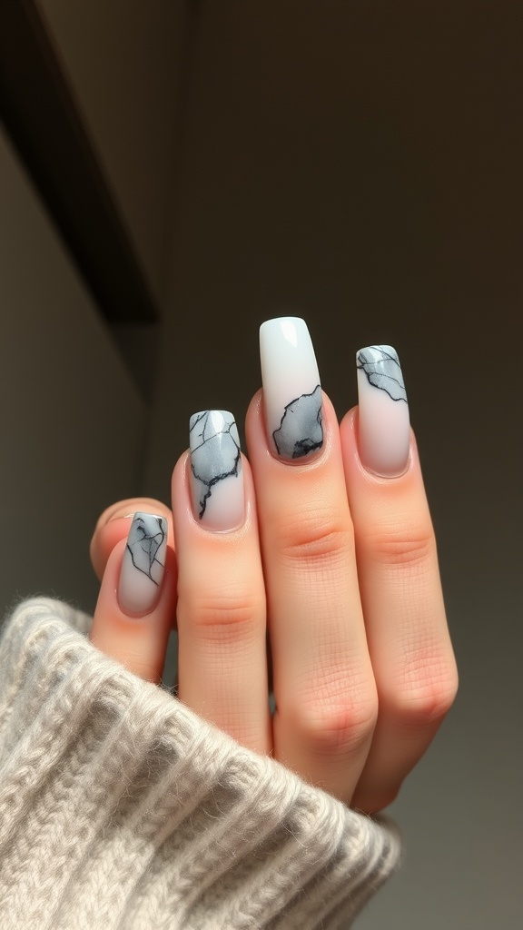 A close-up of acrylic coffin nails featuring a marble effect in black and white, with a cozy sweater in the background.