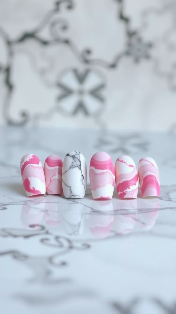 Pink and white marble nail art design with swirls on a marble surface.