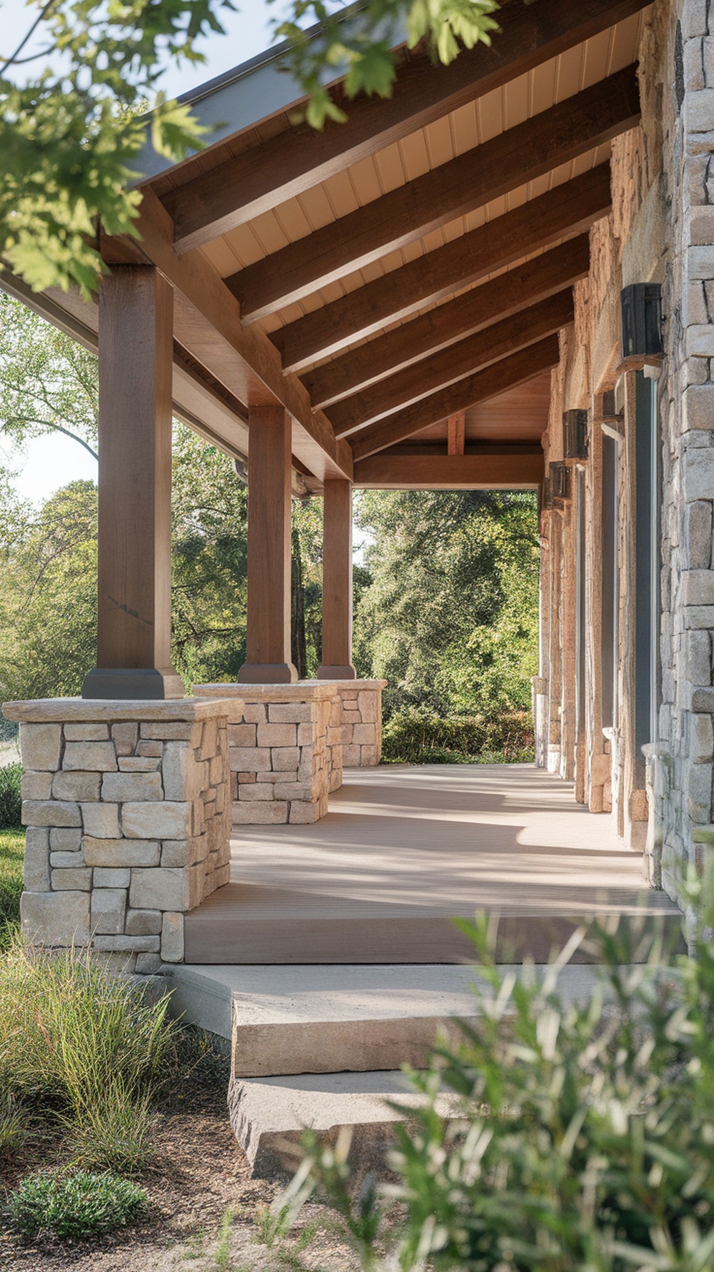 A porch with rough-cut stone columns and smooth cedar beams, surrounded by greenery.