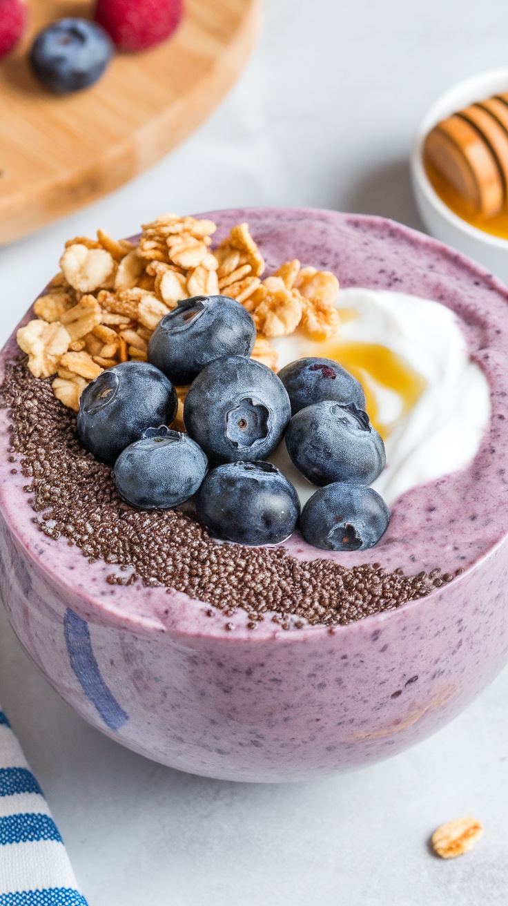 A colorful blueberry chia seed smoothie bowl topped with granola and fresh blueberries.