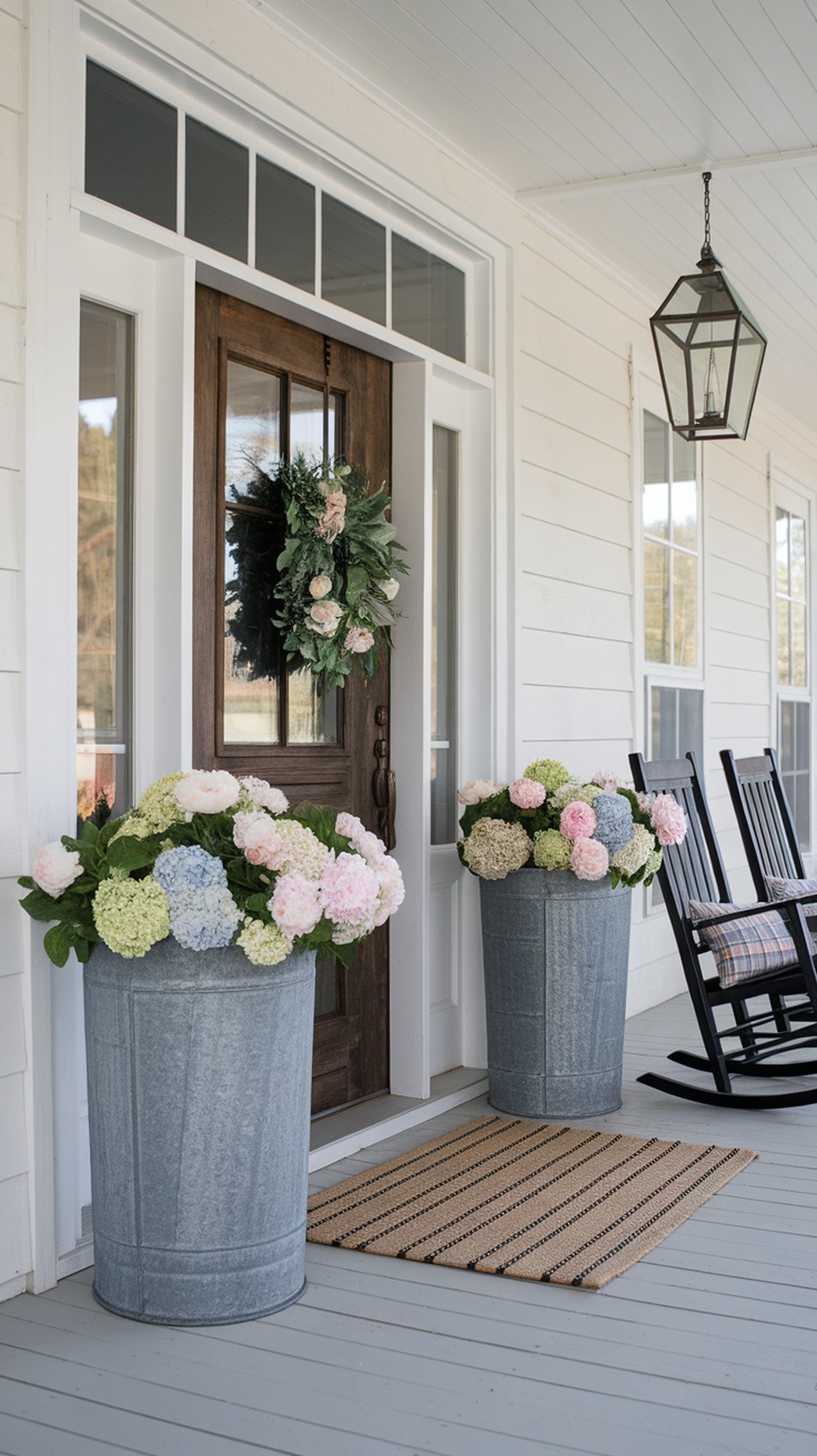 Two galvanized metal flower pots filled with colorful hydrangeas on a farmhouse porch.