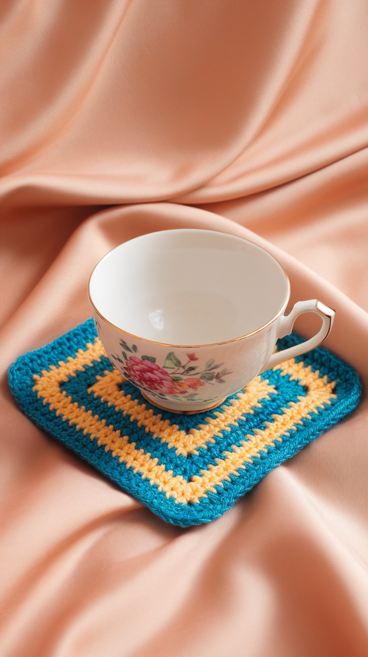 A chevron striped crochet coaster in teal and yellow with a floral cup on top.