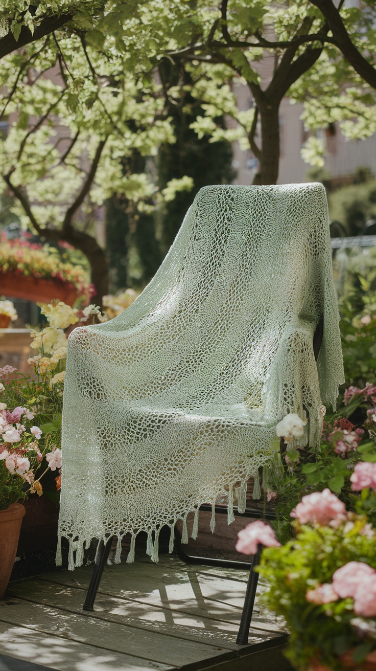 A light green crochet shawl draped over a chair surrounded by blooming flowers in a garden.