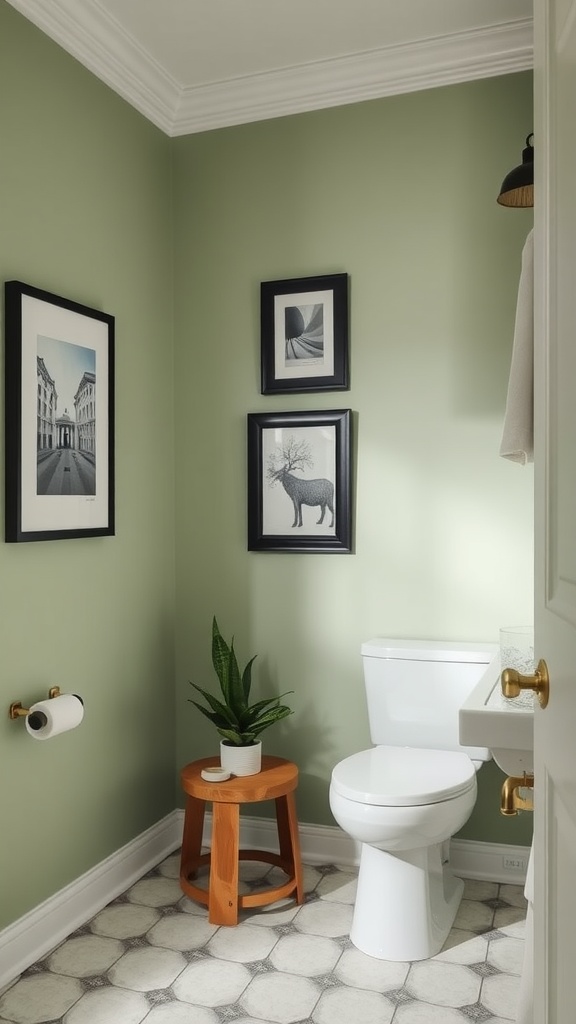 A bathroom featuring a sage green accent wall, black-framed artwork, and a wooden stool with a plant.