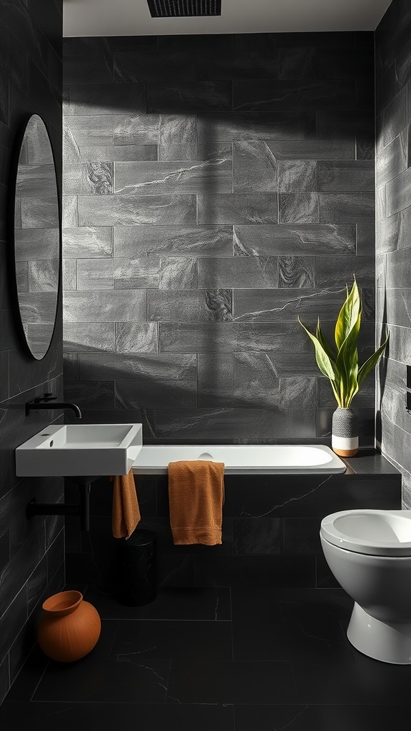 A stylish black tile bathroom featuring a bathtub, sink, and a plant, with vibrant orange towels adding color.