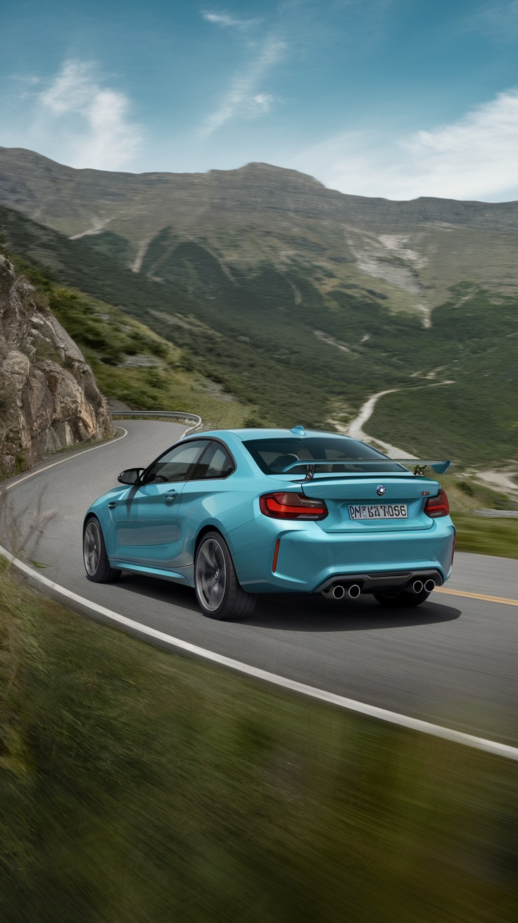 A BMW M2 on a winding road with mountains in the background.