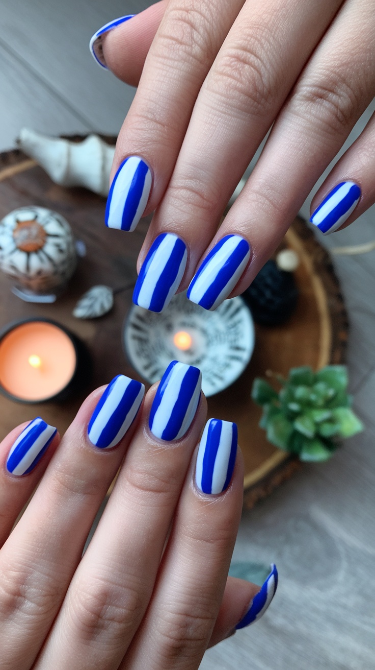 Nails with bold blue and white stripes on a wooden background with candles and decorative items.