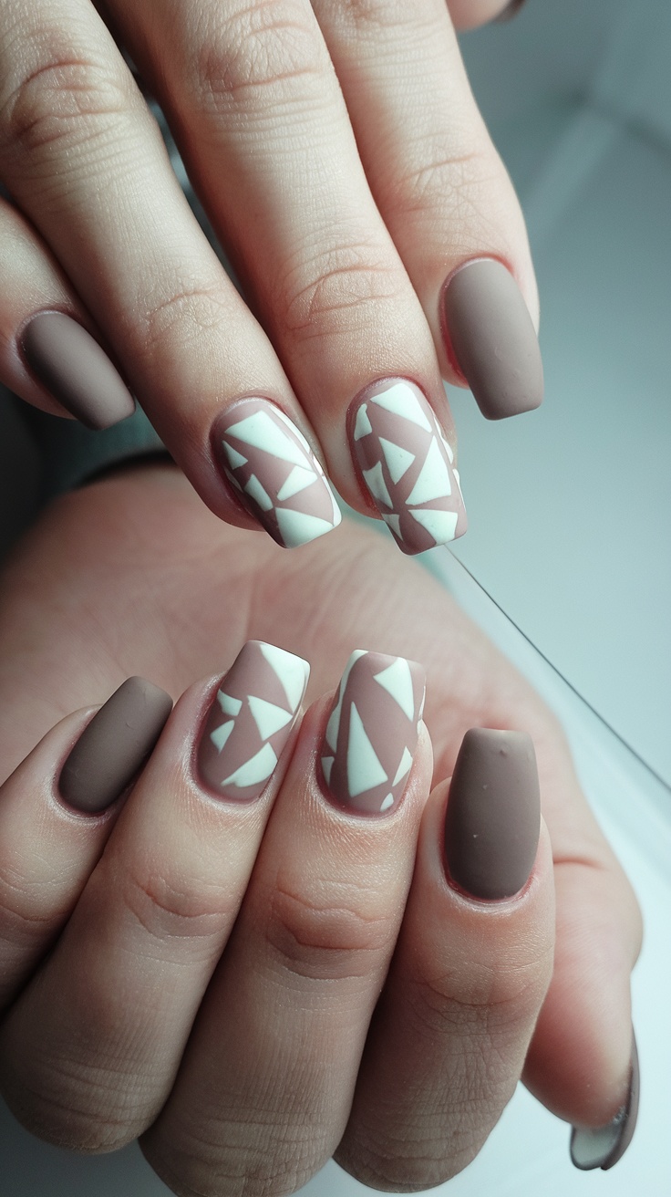 Short nails featuring minimalist geometric patterns in muted colors.
