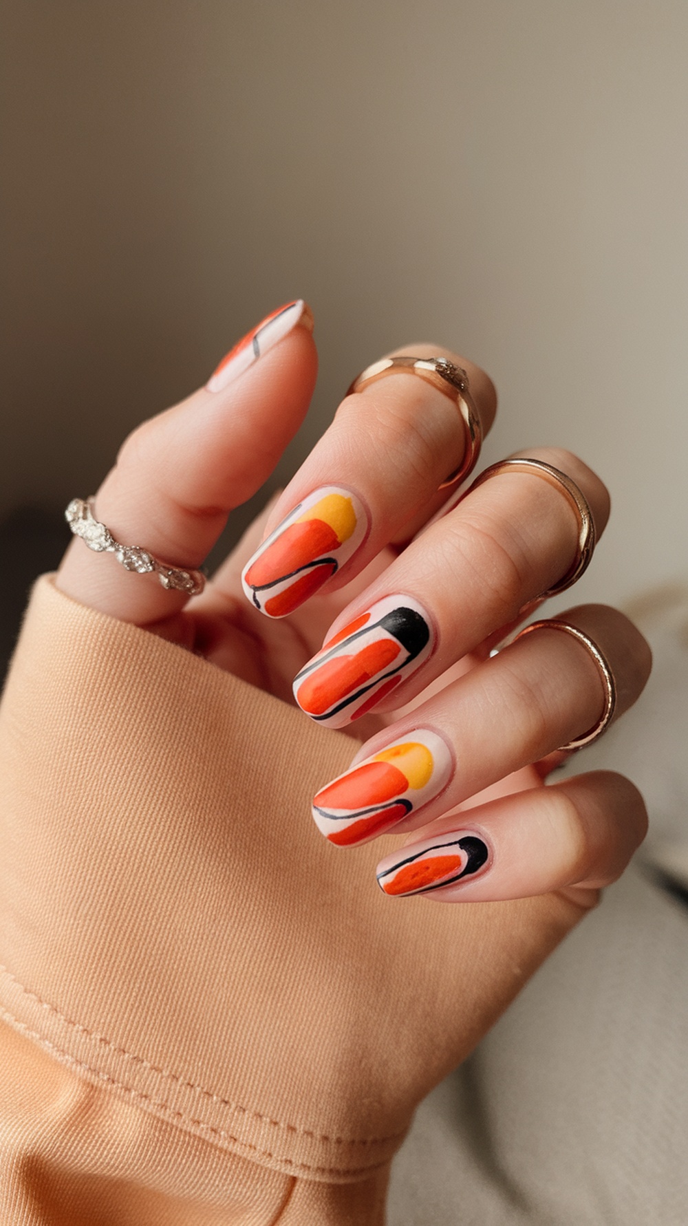 Nails painted with abstract sunset art in orange, yellow, and black colors.