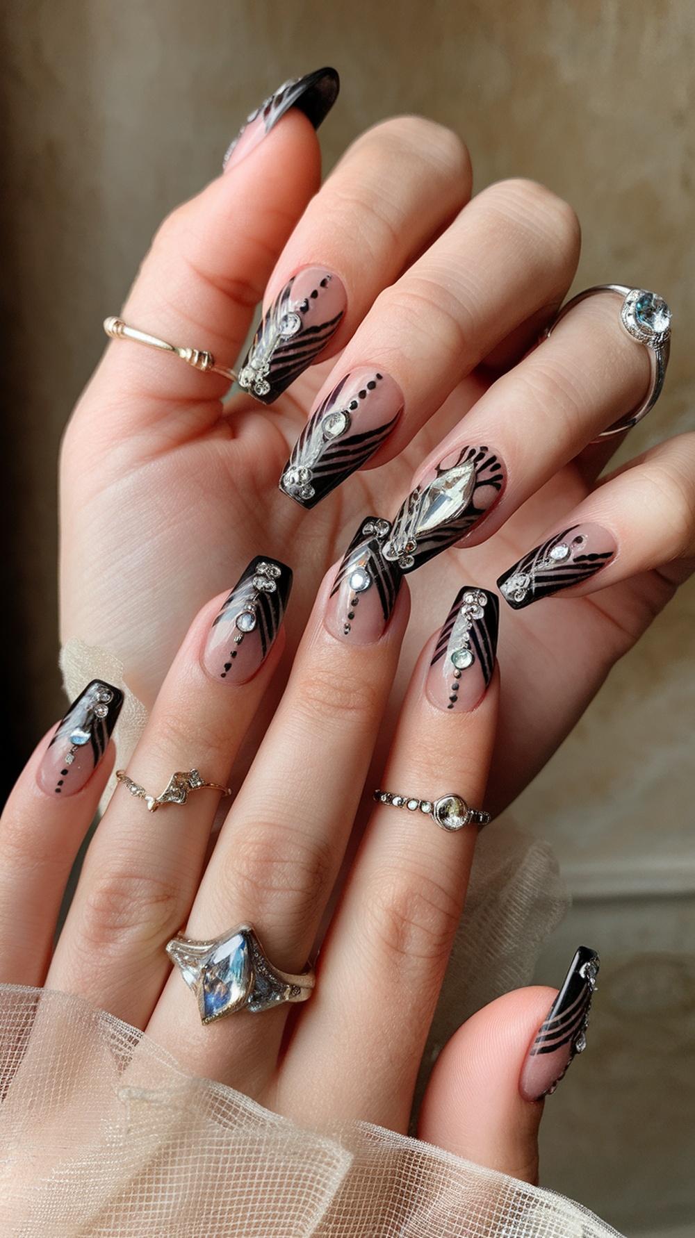 Art Deco inspired nail design featuring black tips, intricate patterns, and rhinestones.