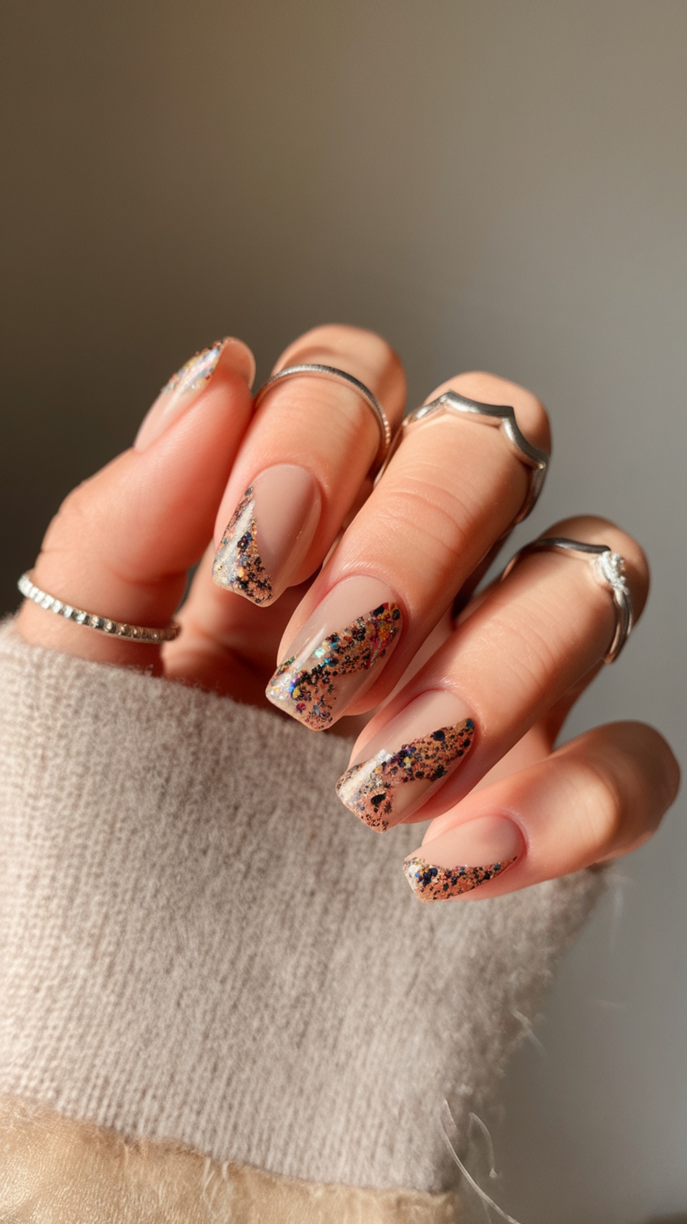 Nails with chunky glitter accents in a nude color