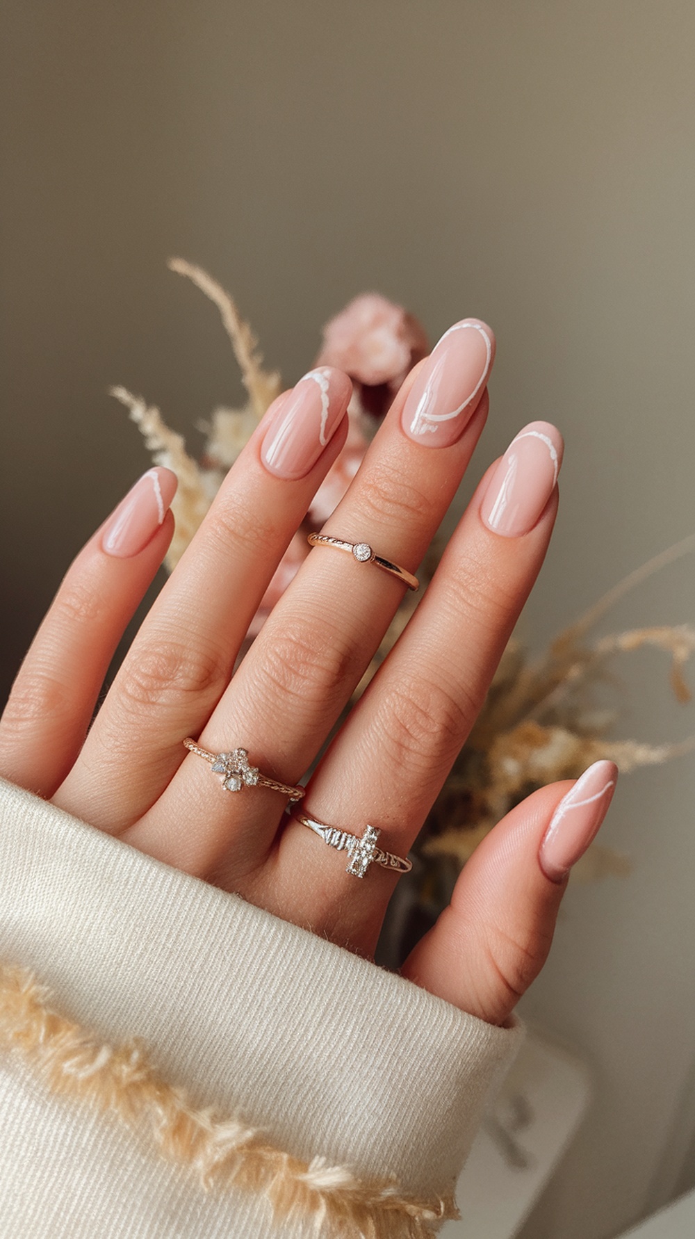 A close-up of elegantly manicured nails featuring a plum color with white accents, showcasing rings on the fingers.