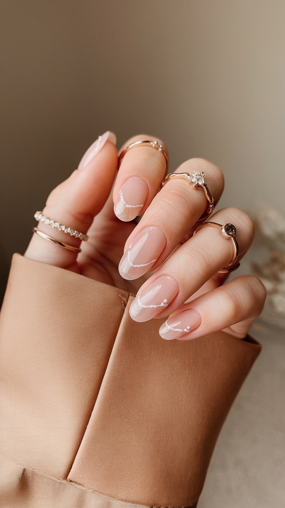 A close-up of slim nails with a stylish French manicure, adorned with rings on fingers.