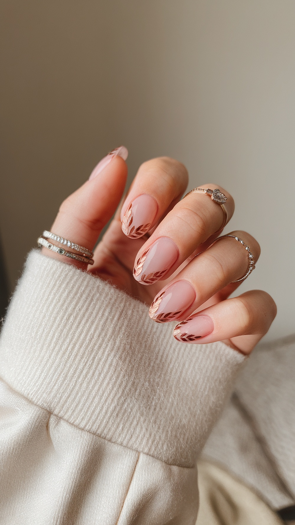 Nails with copper tips and leaf patterns, accessorized with rings