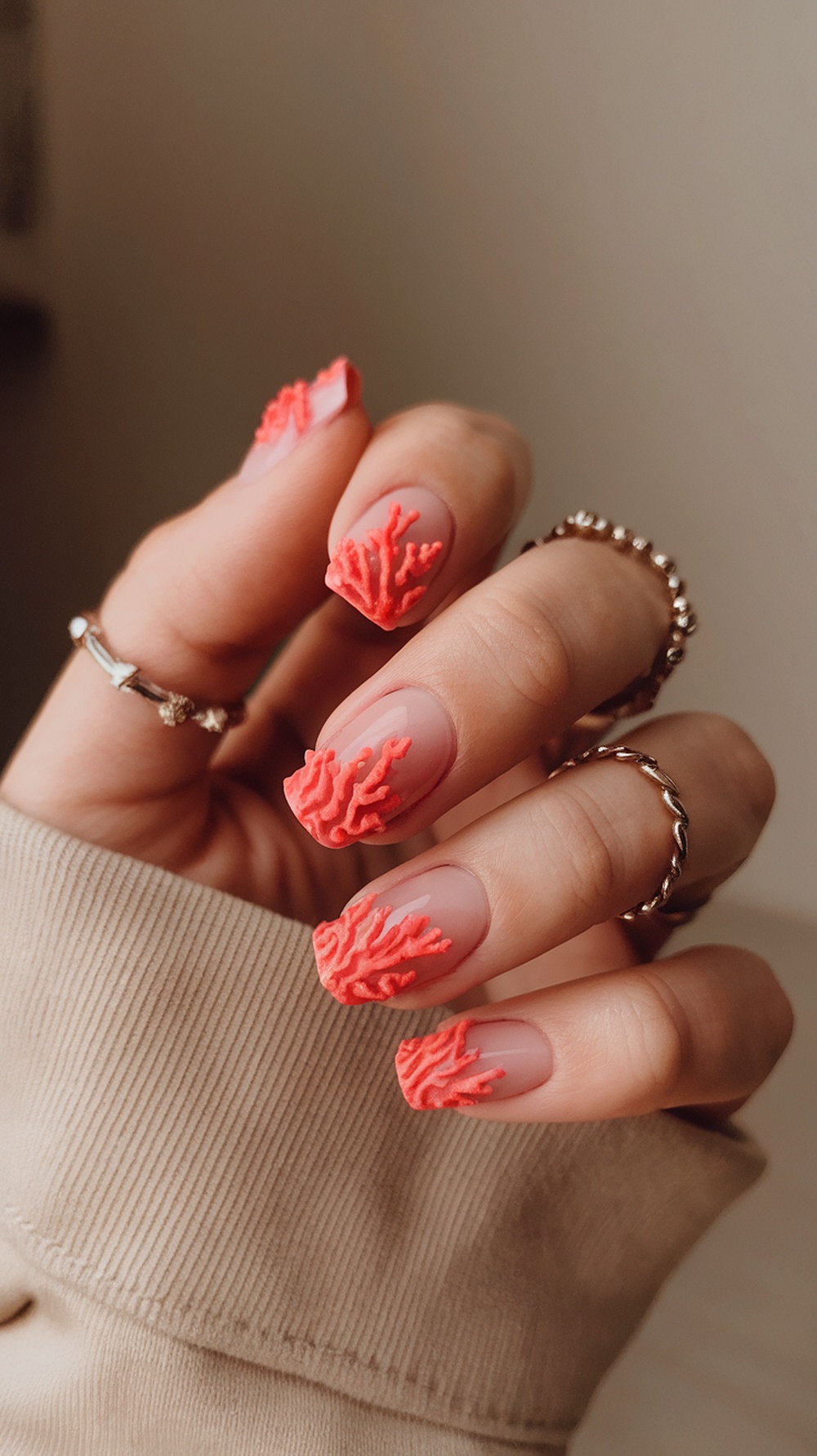 Nails with coral reef inspired design, featuring coral tips on a nude base.