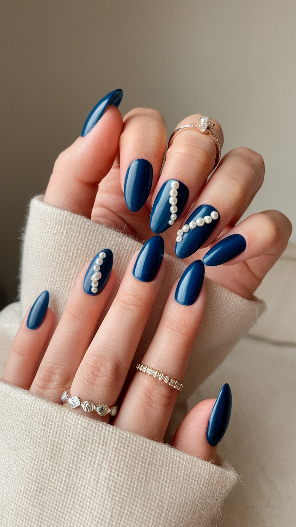 Nails painted in deep sea blue with pearl accents, showcasing a modern and elegant design.