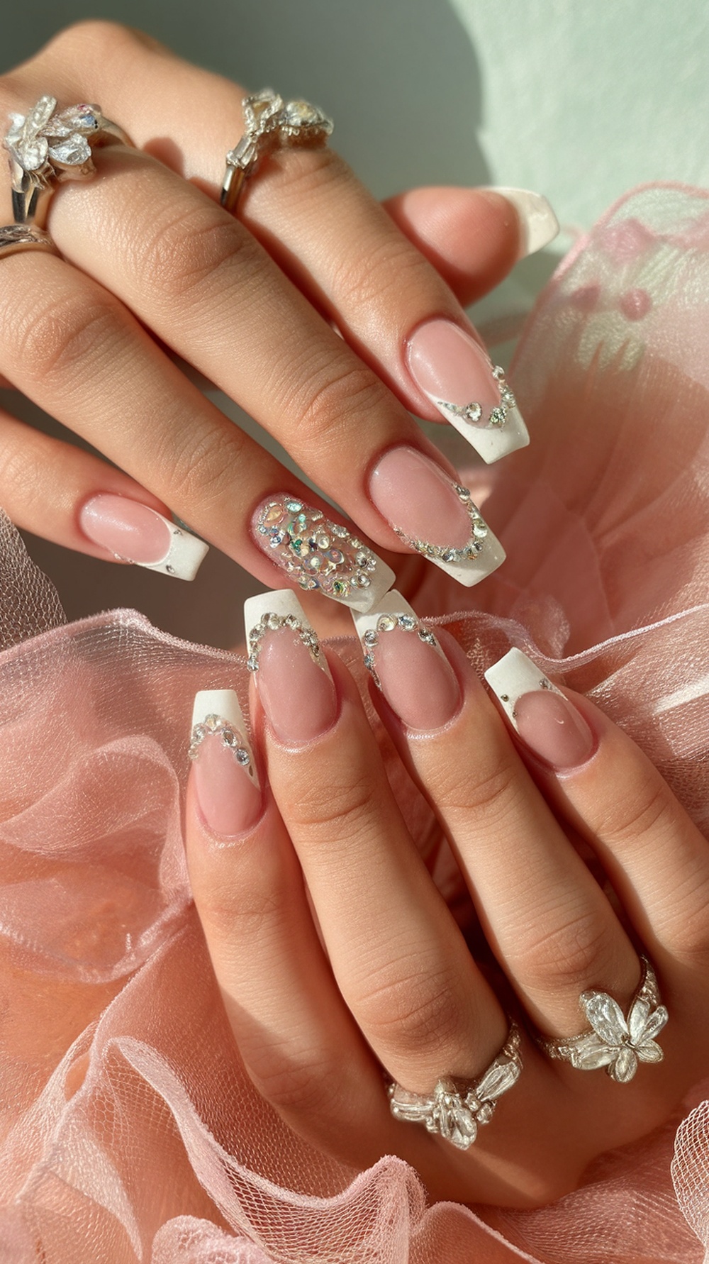 Elegant French tip nails with rhinestones and delicate rings