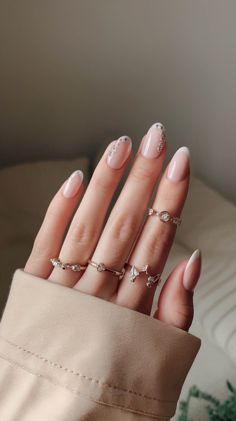 A hand displaying beautifully manicured cotton candy chrome nails with delicate rings.