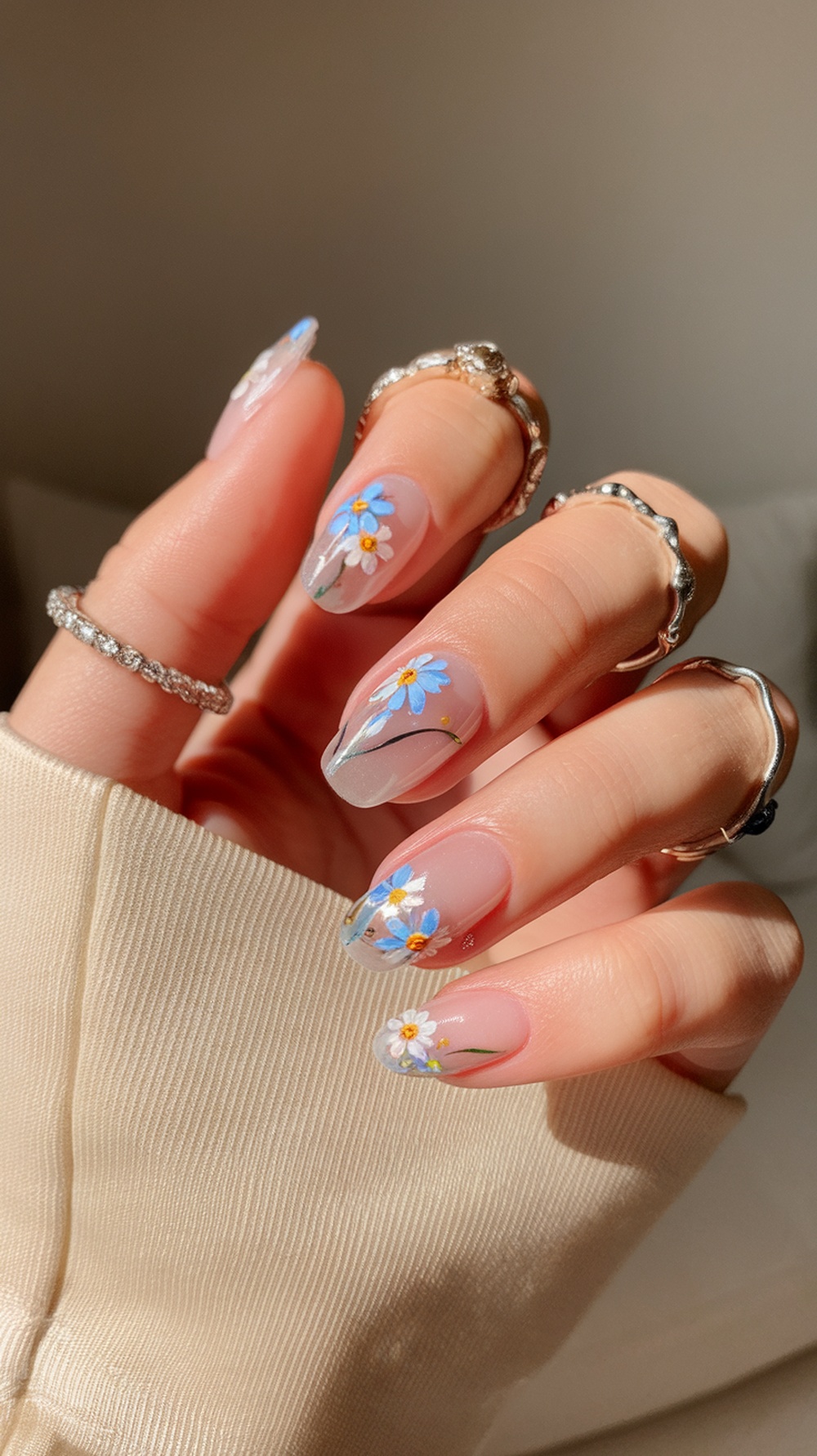 Close-up of floral nail art with blue and white flowers on a light base