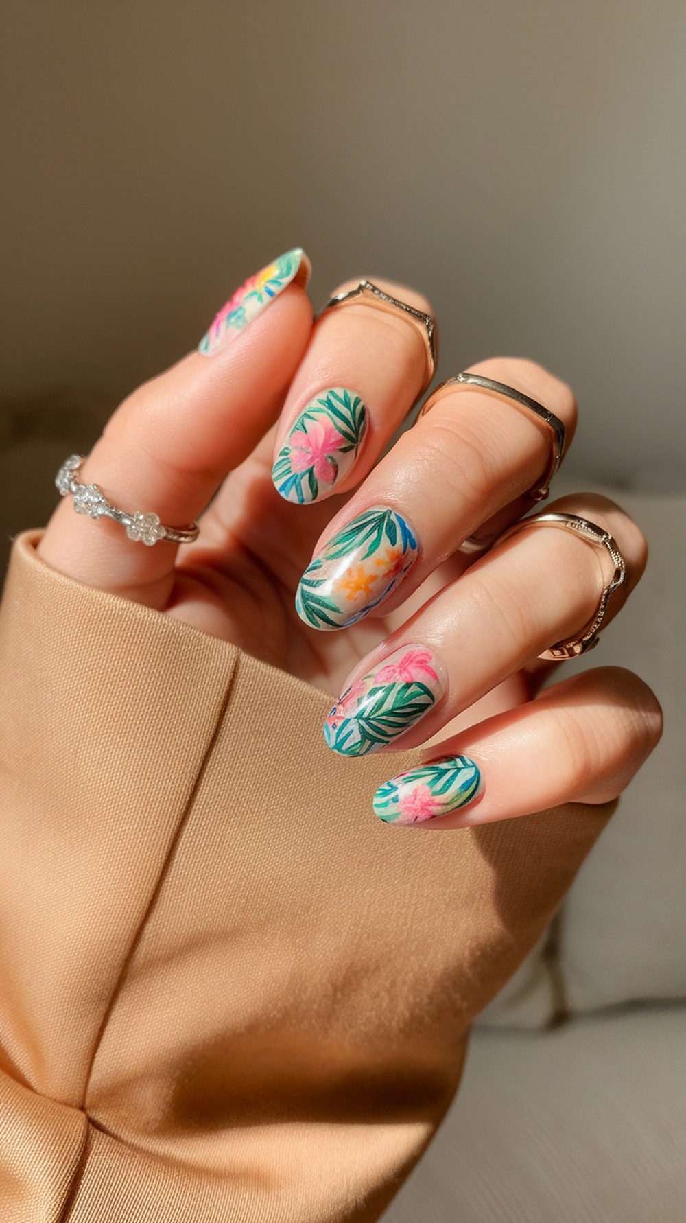 Close-up of hands with floral nail art featuring pink and orange flowers on a green background.