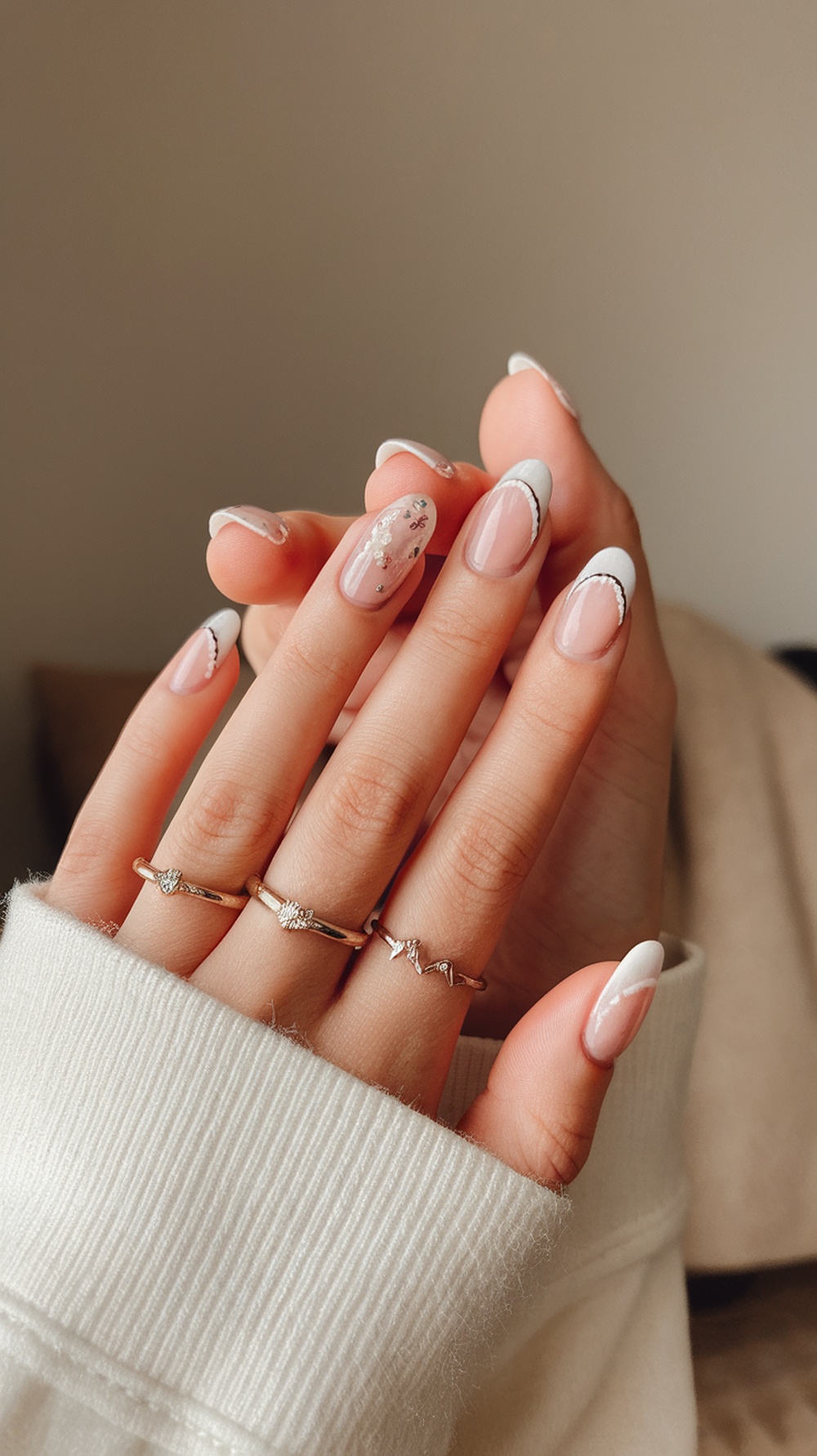Close-up of hands with short summer nails featuring fruit slice decals and delicate rings.