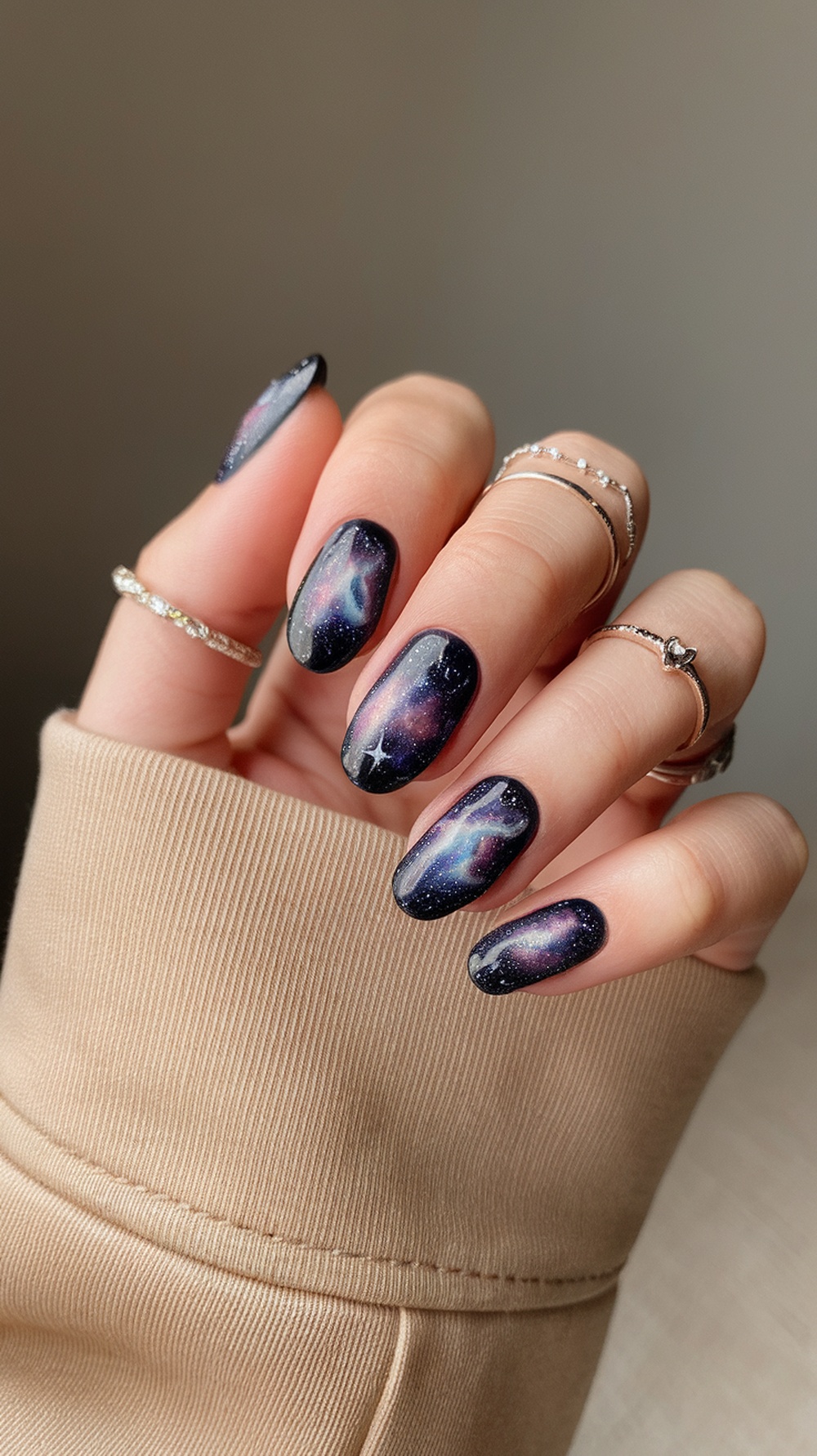 Close-up of galaxy-inspired nail art with dark colors and sparkles.